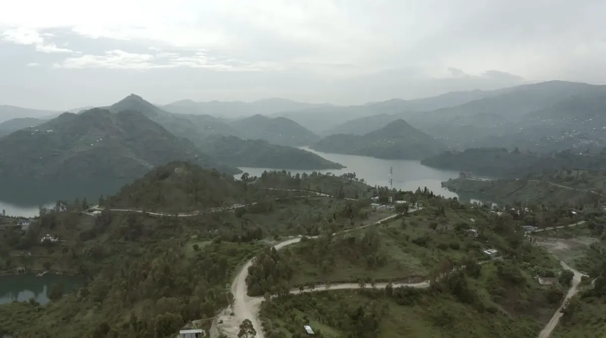 Green hills and a lake in Rwanda under a cloudy sky